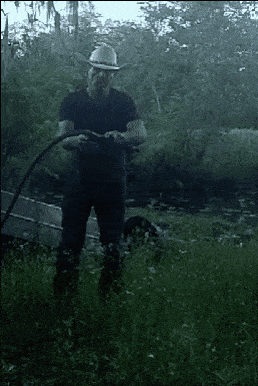 a man in a cowboy hat is holding a hose in his hands