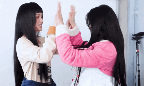 two girls are giving each other a high five while wearing matching sweaters