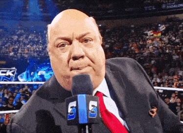 a man wearing a suit and tie stands in front of a microphone with the number 5 on it