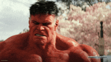 a red hulk is standing in front of a tree with flowers