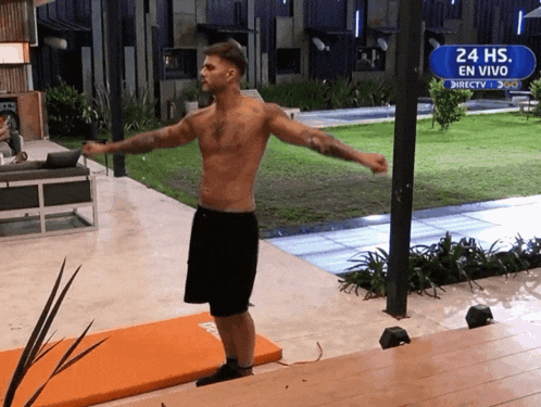 a shirtless man is doing exercises in front of a sign that says 24 hs en vivo
