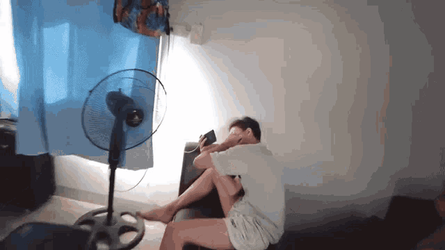 a person is sitting in front of a fan in a room .