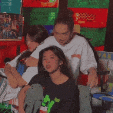 three girls are posing for a picture in front of a wall with crates on it
