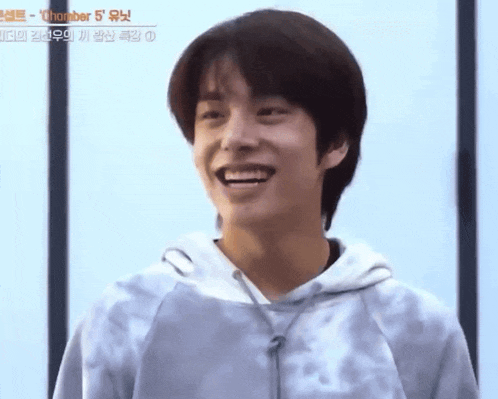 a young man in a tie dye hoodie is smiling and looking at the camera .