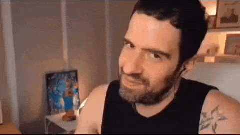 a man with a beard and a tattoo on his arm is wearing headphones and making a funny face .