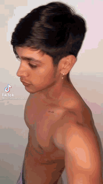 a young man without a shirt has a tattoo on his chest