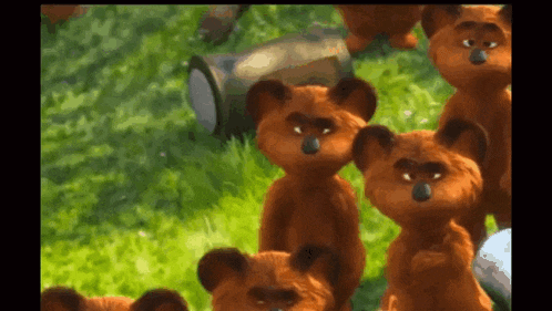 a group of teddy bears are standing in the grass looking at the camera .