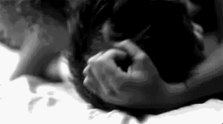 a man and a woman are laying on a bed holding each other 's faces .