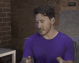 a man in a purple shirt is sitting in front of a microphone and talking into it .