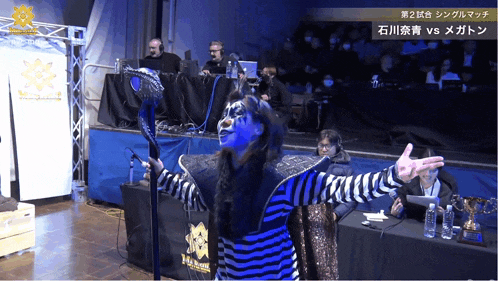 a person with blue paint on their face is standing in front of a table with a sign that says ' megaton ' on it