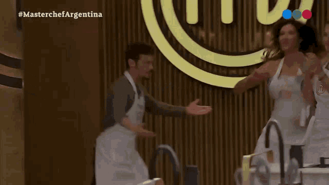 a group of people dancing in front of a masterchef sign