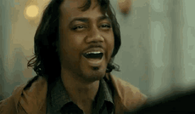 a man with a beard is laughing with his mouth open .