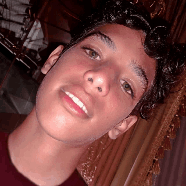 a close up of a young man 's face with a red shirt on