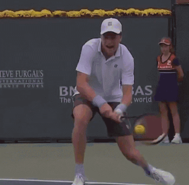 a man is playing tennis in front of a steve furgal 's international tennis court sign