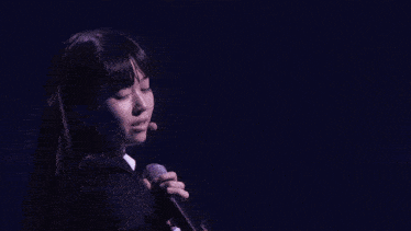 a girl with a microphone in her ear holds up her hand