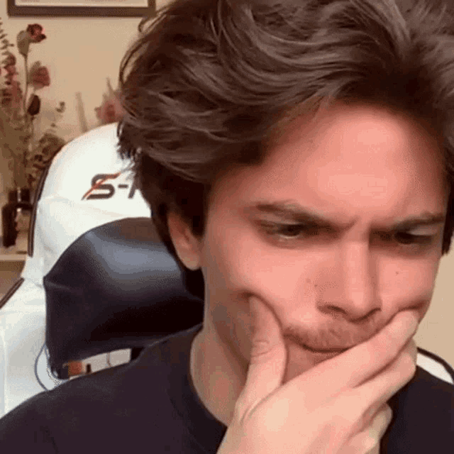 a young man is making a funny face while sitting in a chair .