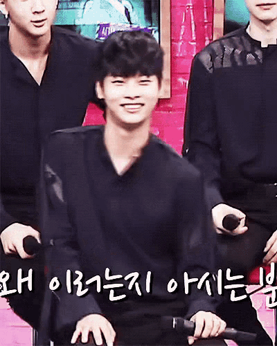 a man in a black shirt is smiling while holding a microphone in his hand