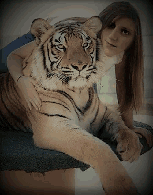 a woman is sitting next to a tiger on a table