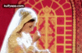 a woman in a white dress and veil is standing in front of a window .