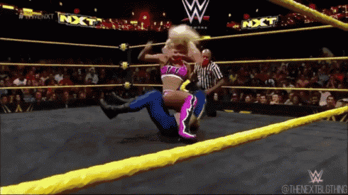 a woman is wrestling a man in a wrestling ring that says nxt on the ropes