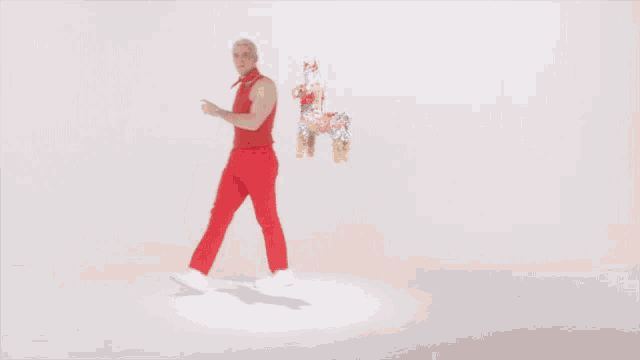 a man in red pants and a red tank top is holding a yellow object