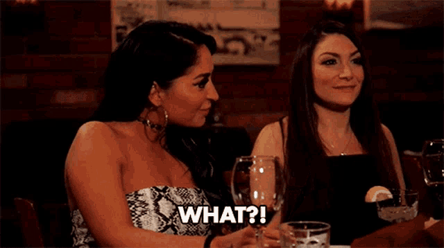 two women are sitting at a table and one of them is asking what