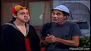 two men are standing next to each other and talking to each other . one of the men is wearing a hat .