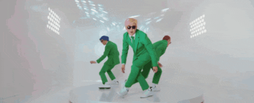 a group of men in green suits are dancing