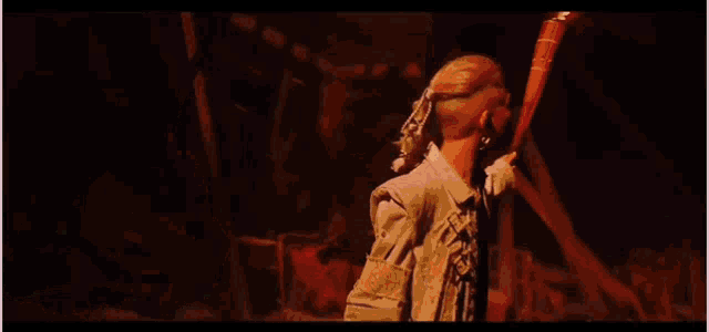 a woman in a white jacket is holding a baseball bat in a warehouse .