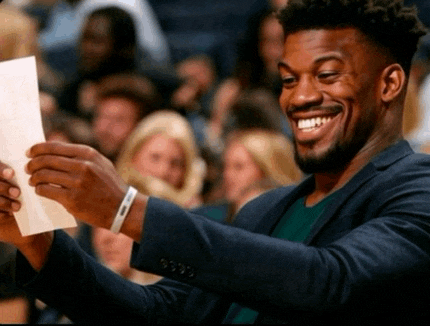 a man in a suit is smiling while holding a piece of paper in front of a crowd