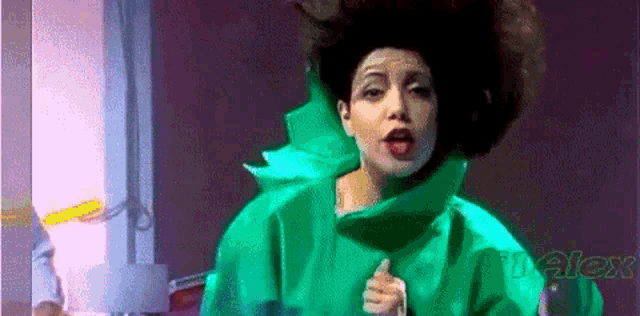 a woman in a green dress is singing into a microphone with the word voice in the corner