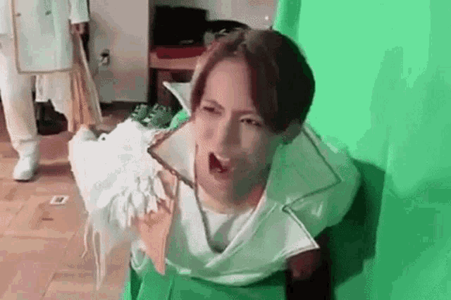 a man in a green and white costume is sitting on a green screen .