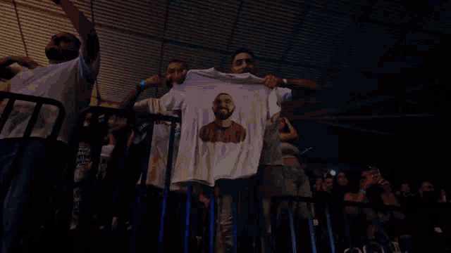 a man is holding up a shirt with drake on it