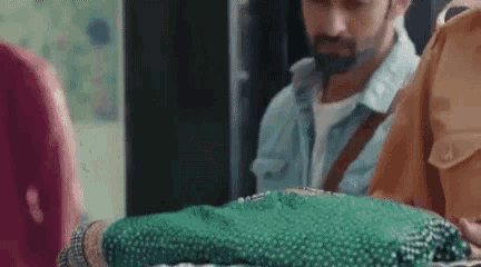 a man is standing next to a woman holding a green item .