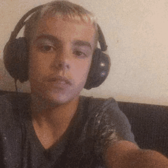 a young man wearing headphones takes a picture of himself
