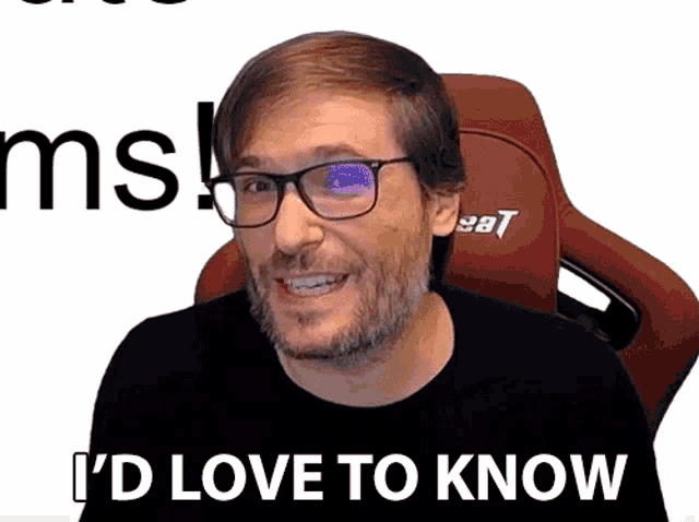 a man with glasses and a beard says " i 'd love to know " while sitting in a red chair