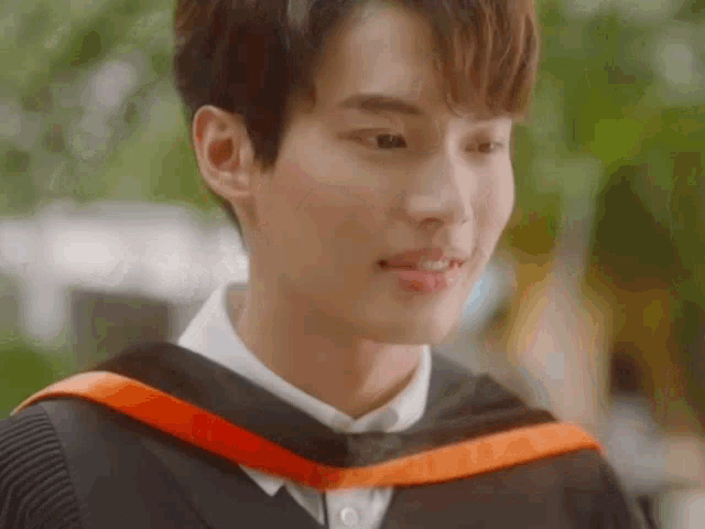 a young man is wearing a graduation cap and gown and smiling .