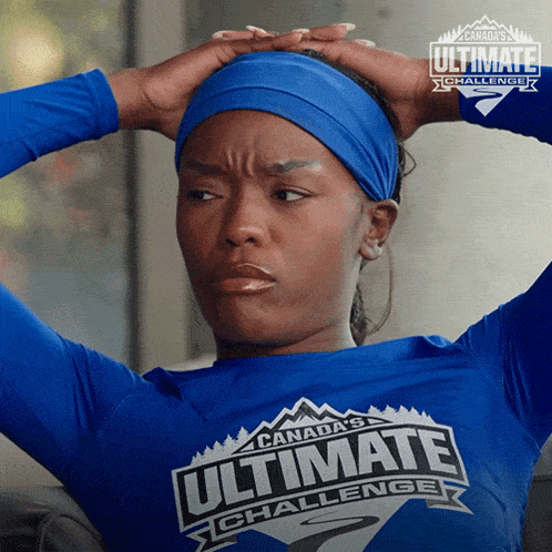 a woman wearing a canada 's ultimate challenge shirt holds her head