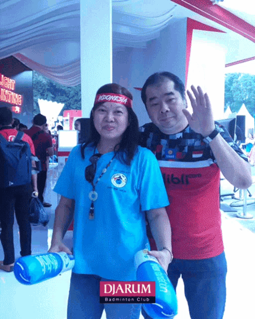 a man and a woman are posing for a picture in front of a sign that says djarum