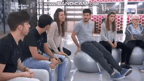 a group of people are sitting on exercise balls on a bench .