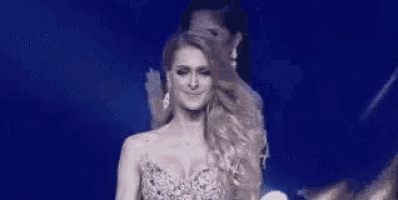 a woman in a dress is standing on a stage with a woman covering her face .