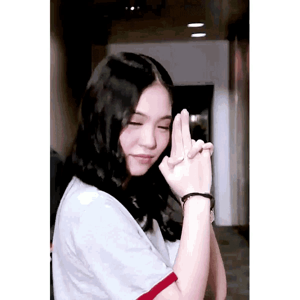 a young woman is making a heart with her hands .