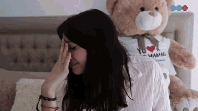 a woman sitting next to a teddy bear wearing a shirt that says i love you mama