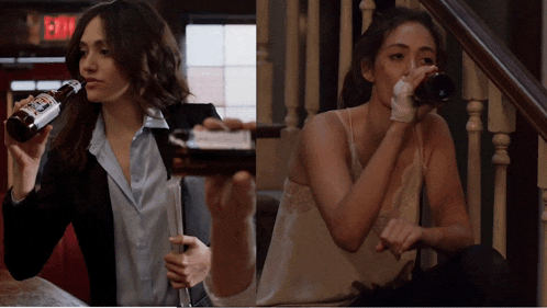 a woman drinking a bottle of beer next to a woman sitting on a staircase