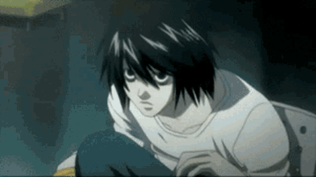 a man with black hair and white eyes is sitting down in a dark room