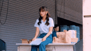 a woman is sitting on a desk with a clipboard in her hand