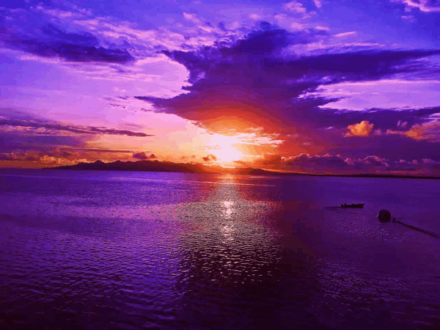 a sunset over a body of water with a boat in the distance