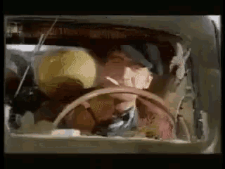a man is sitting in the back seat of a car with a steering wheel .
