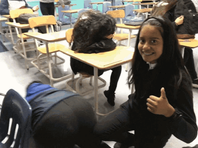 a girl is giving a thumbs up in a classroom