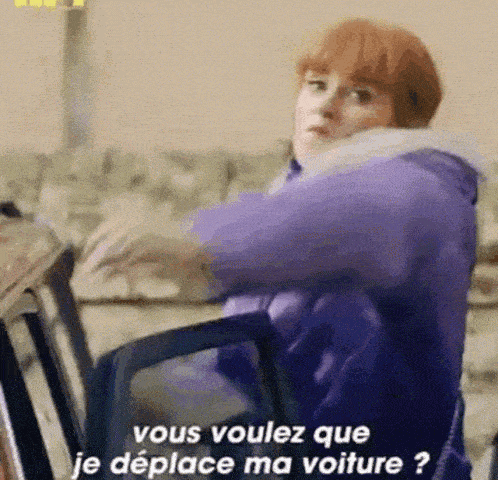 a woman in a purple jacket is sitting in a chair and talking in french